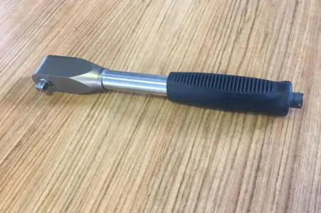 Grey and silver torque wrench on a wooden table