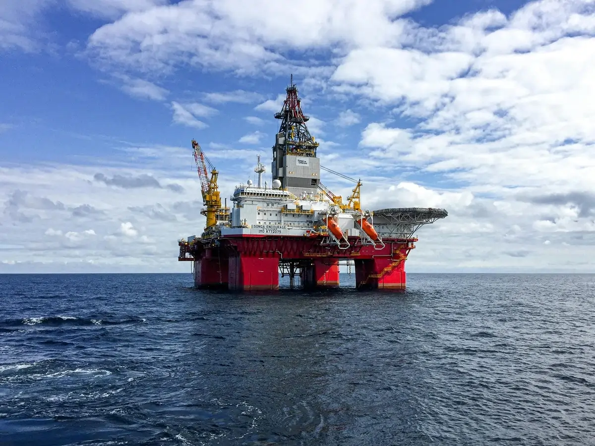 Oil rig in the middle of the ocean with blue sky and clouds